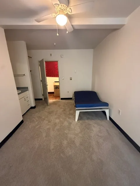 Studio apartment with kitchenette, ceiling fan, and bed at Barbara Maher Apartments
