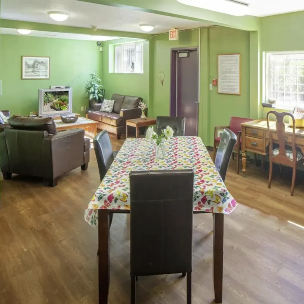 Community room with dining table, sofas, and TV at Barbara Maher Apartments