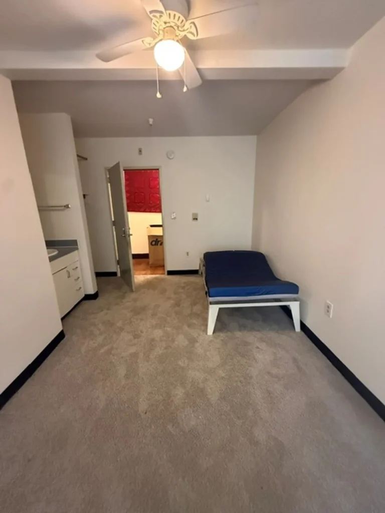 Studio living area with kitchenette and ceiling fan at Barbara Maher Apartments